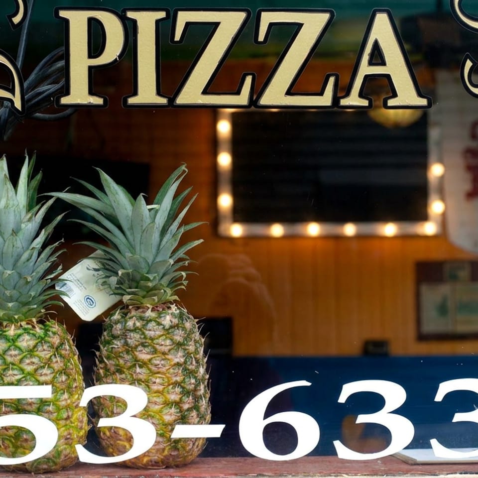 Restaurant window displays three pineapples, large pizza lettering, and phone number 853-6337.